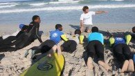 Take a first glance at this gaggle of teenagers stood round in a huddle on one of the most picturesque beaches in Cape Town and you’d be forgiven for thinking it was a bunch of mates about to catch some after-school surf. But get closer and you’d see there’s a coach stood among them, raising his voice so he can be heard over the crashing wave break, he says “so tell me, how does it feel to be pushed around?”